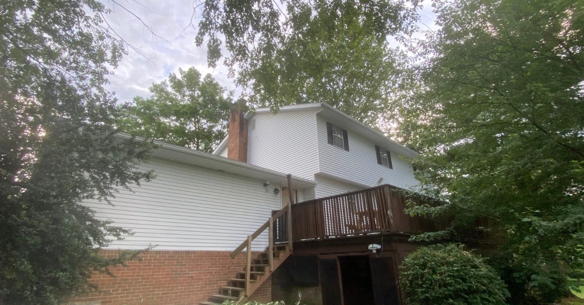 Exterior repaint of a home with white siding and deck